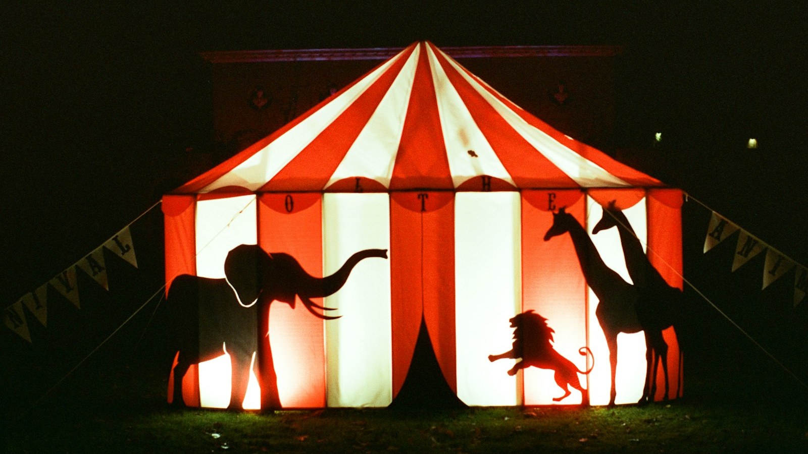 Lona de circo iluminada com silhuetas de animais recortadas