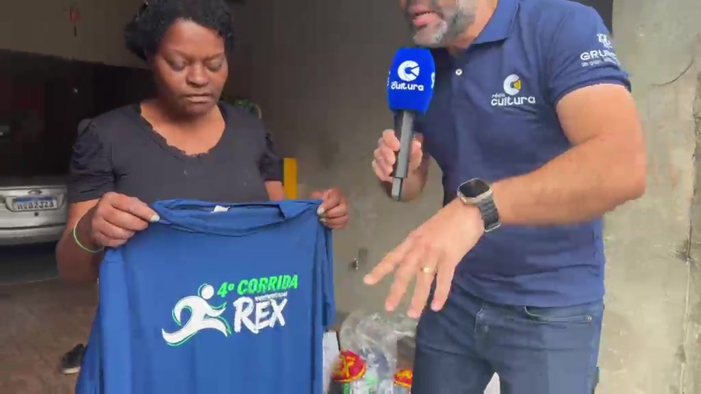 Camisas azuis da 4ª Corrida Rex sendo mostradas durante a entrevista