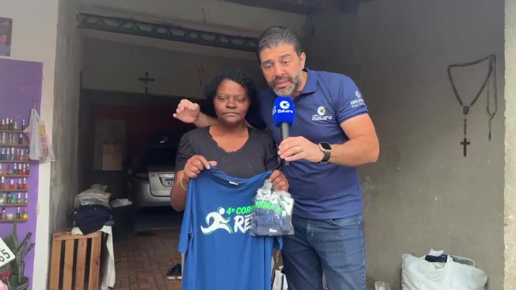 Tia Lu recebe camisas e um pacote de doações na porta de casa, no Vila Rica