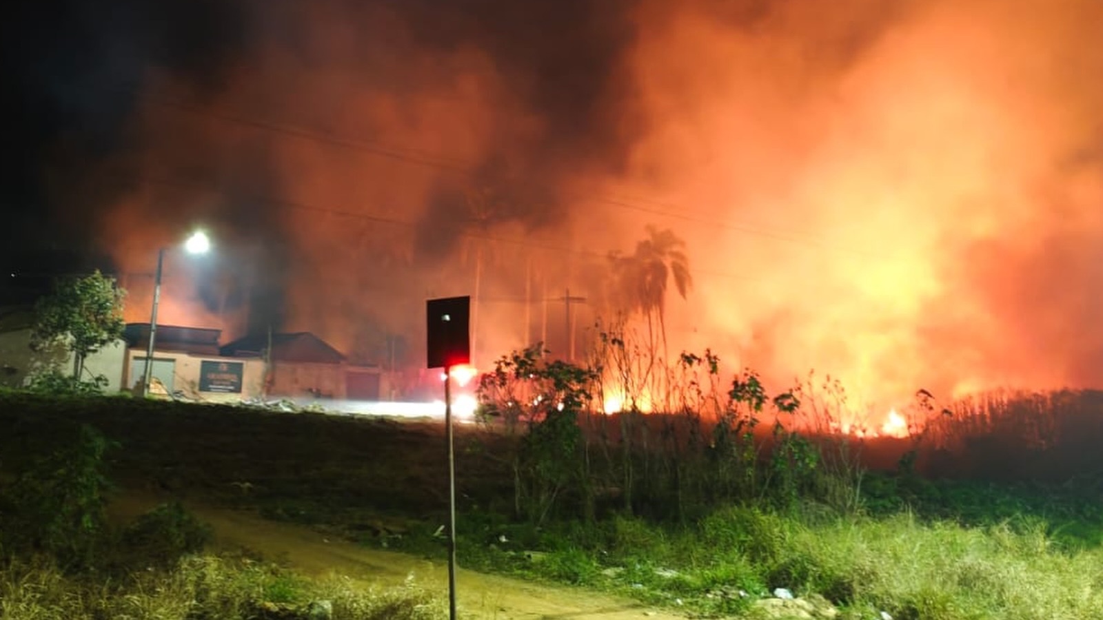 As chamas avançam pela vegetação a poucos metros das casas, no alto da Cohab, em Lavras, na noite desta sexta-feira (14)