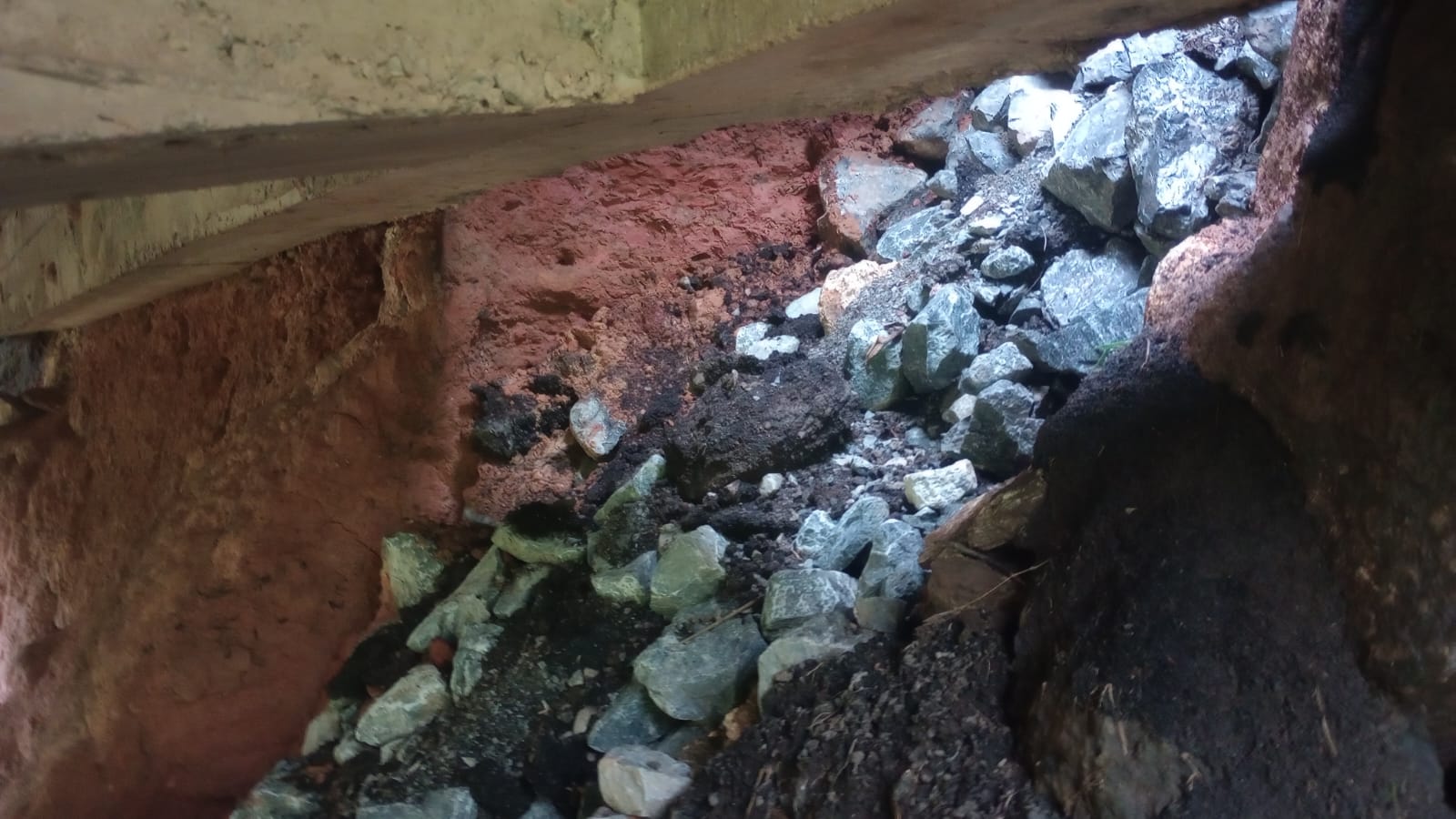 Pedras e terra expostas pela erosão sob a pista da BR-265.