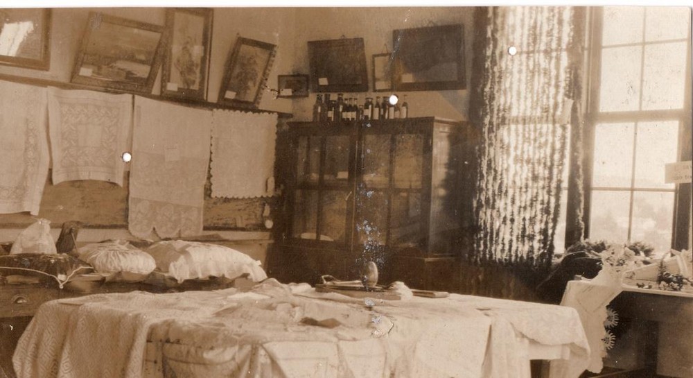 Exposição dos trabalhos manuais das alunas, com bordados, toalhas e almofadas expostos na sala, em imagem sem data do acervo