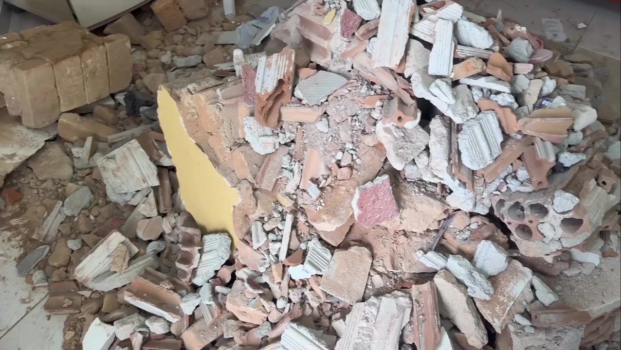 O cômodo atingido: a parede virou lona, e os tijolos ficaram no chão, entre os móveis da casa · Foto: Gabriel Dinali/Rádio Cultura de Lavras