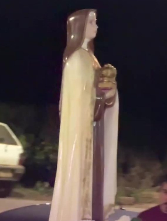 Imagem de Santa Edwiges completa sobre o andor, à noite, durante a procissão
