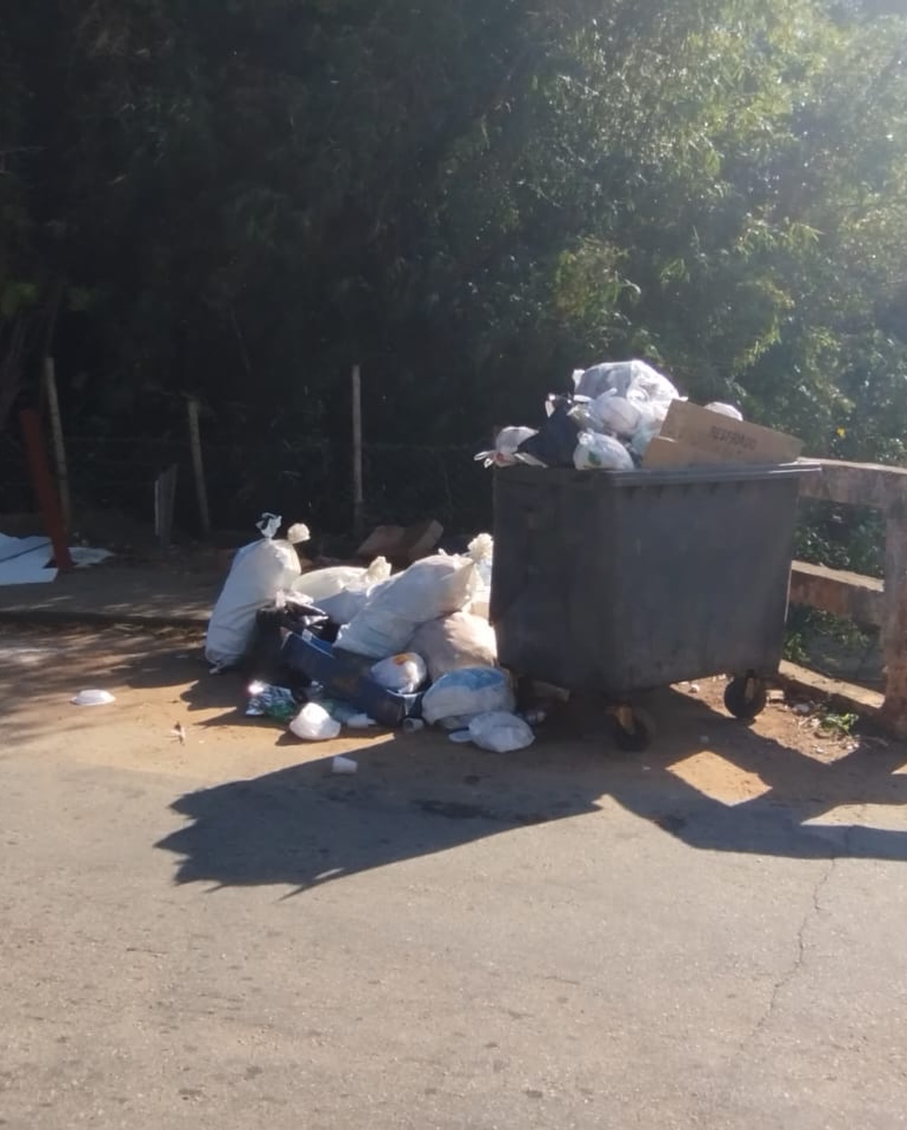 Vista do Ribeirão da Água Limpa com colchão e lixo acumulados sobre as pedras, em Lavras